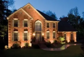 Lit brick house at night with landscape lighting.