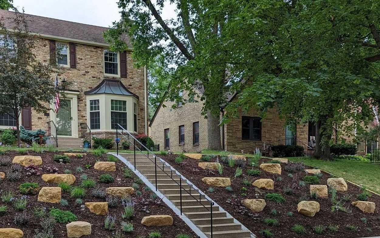 A large house with a lush green lawn and flowers in front of it.