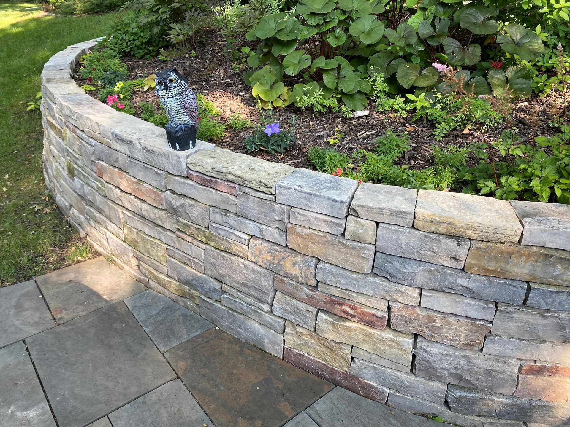 A grill is sitting on a patio next to a brick wall.