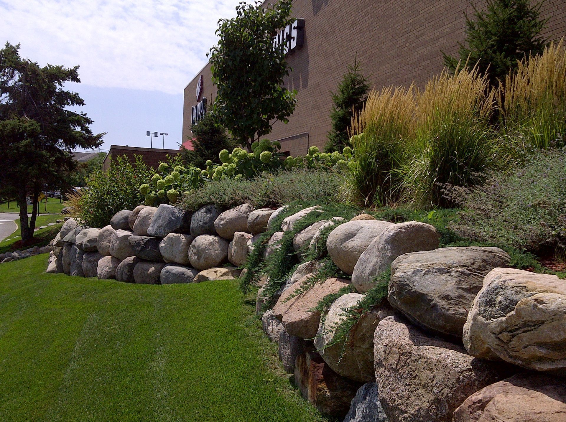A large stone wall surrounds a lush green field