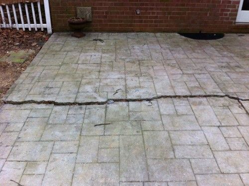 Cracked concrete patio with a brick wall backdrop.
