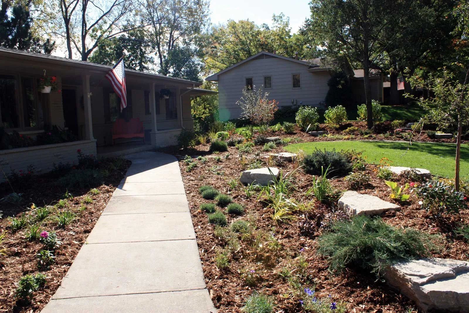 Front yard with large planting beds and gray-white limestone boulder outcroppings in Edina MN