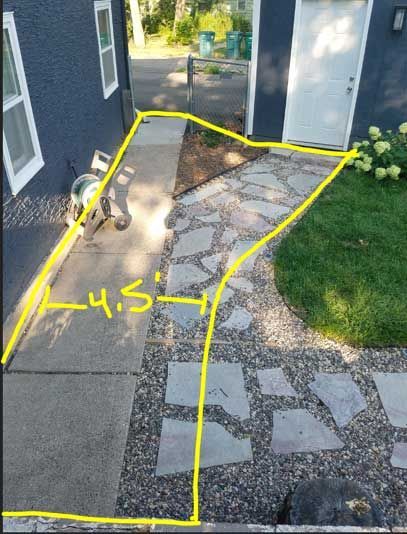 A walkway transitioning from concrete to stone pavers and gravel. A yellow line outlines the pathway.