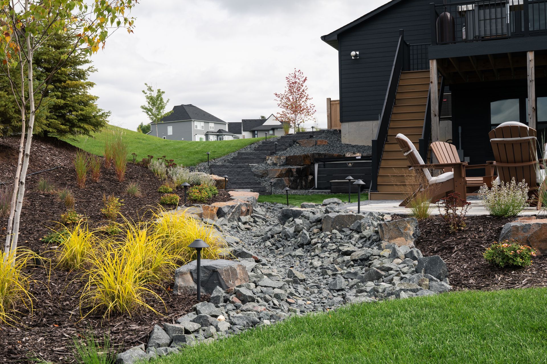 dry creek bed at residential home with river rock boulders and nice looking plantings in the landscaping