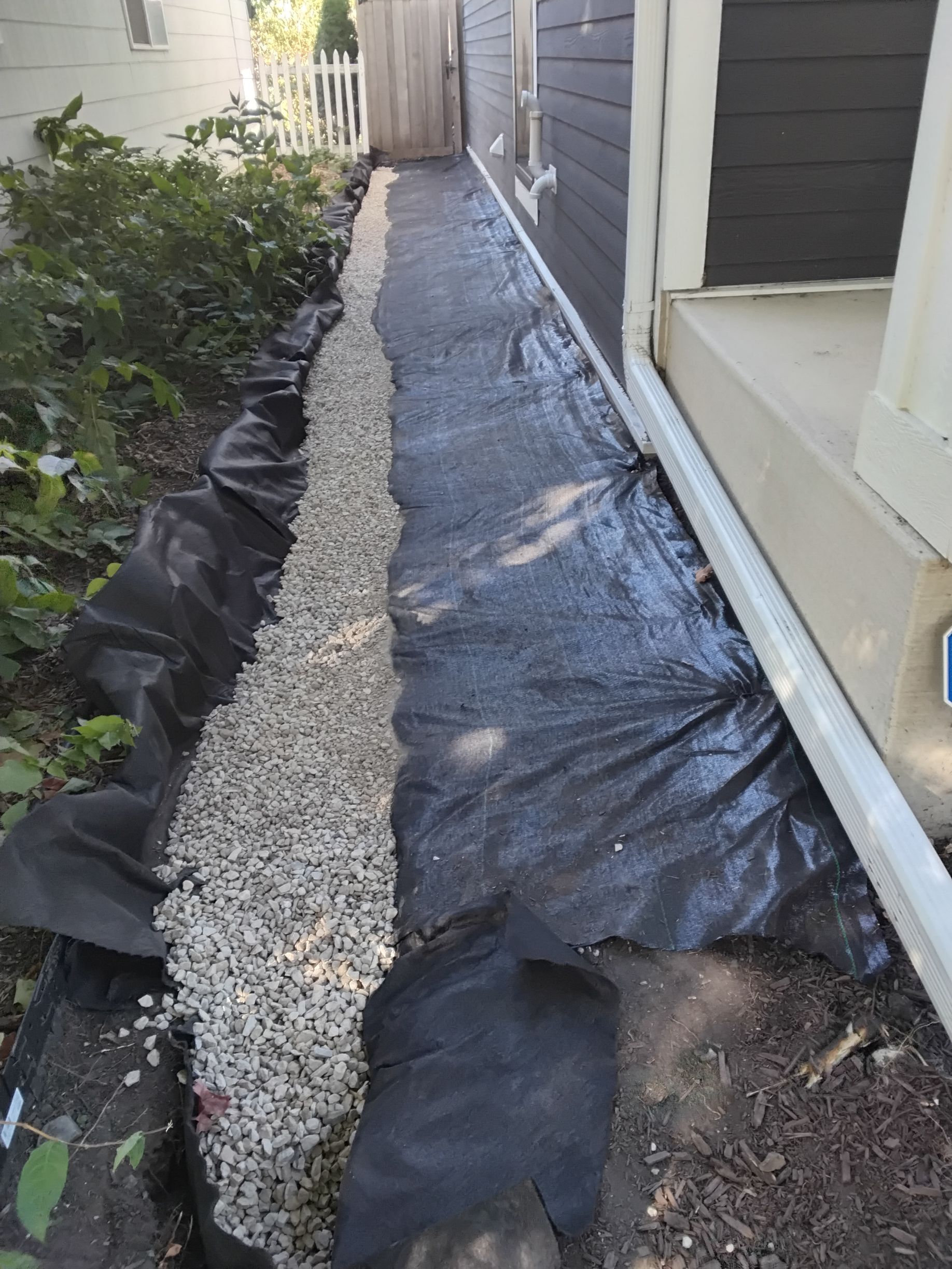 (During) our crew backfilling the drain tile perforated pipe with 3/4 inch rock to cover French drain in Minneapolis 