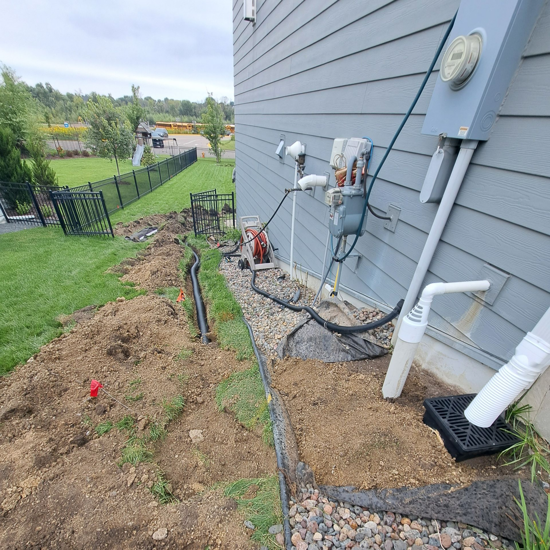 during picture of KG Landscape crew installing a underground gutter drain in Plymouth MN that is tied in with a sump pump discharge drain below ground in Plymouth MN 