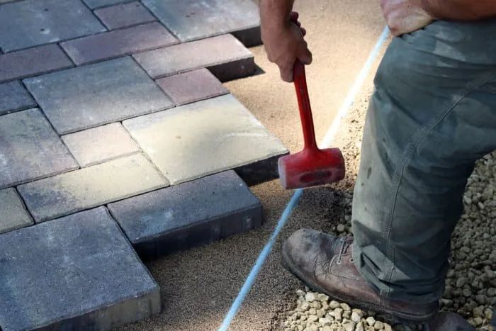 installing pavers with sand and mallet