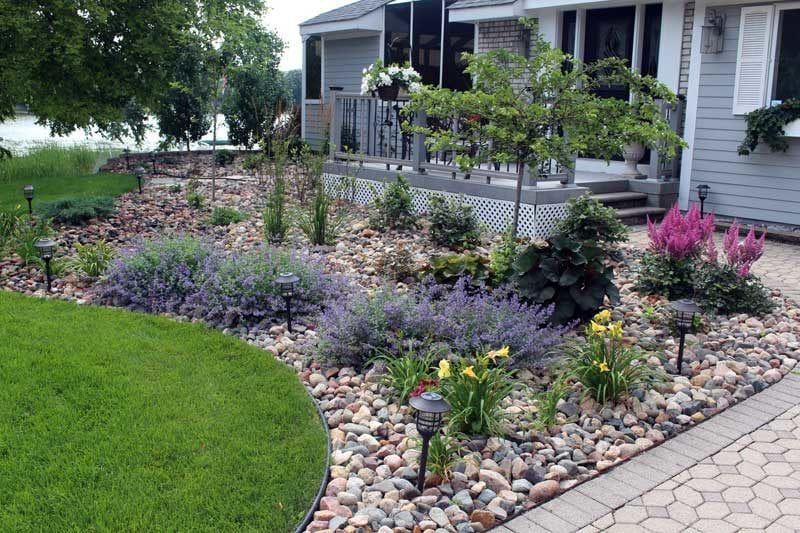 Curved river rock plant bed softening a front deck with Tina crab focal tree and catmint in Minneapolis MN