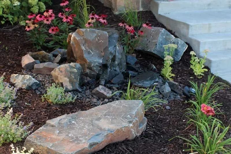 Front yard boulder outcropping with a pondless bubbling rock water feature and flowers in Chanhassen MN