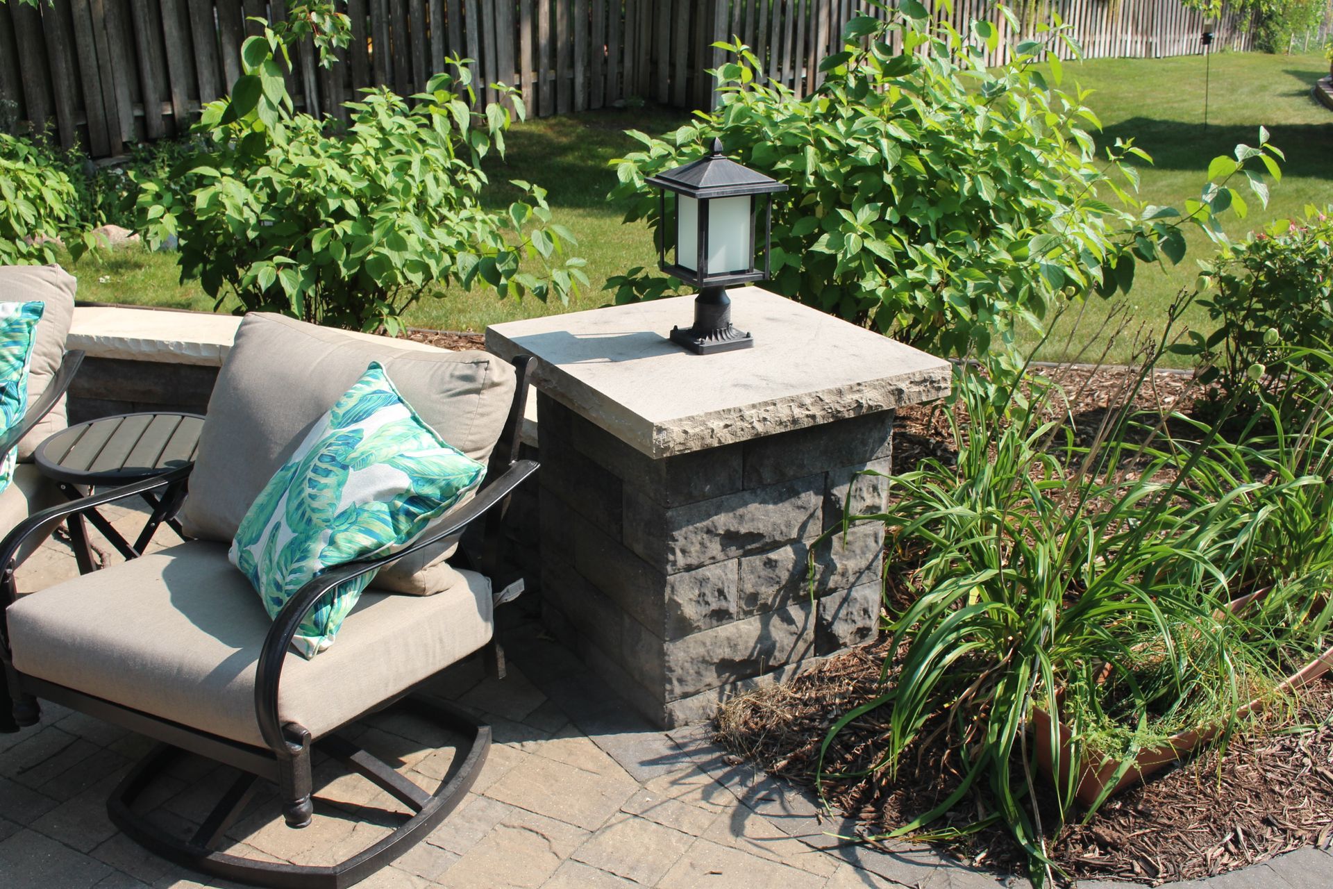 Stone column with light fixture and limestone-capped sitting wall around a paver patio in Shoreview MN