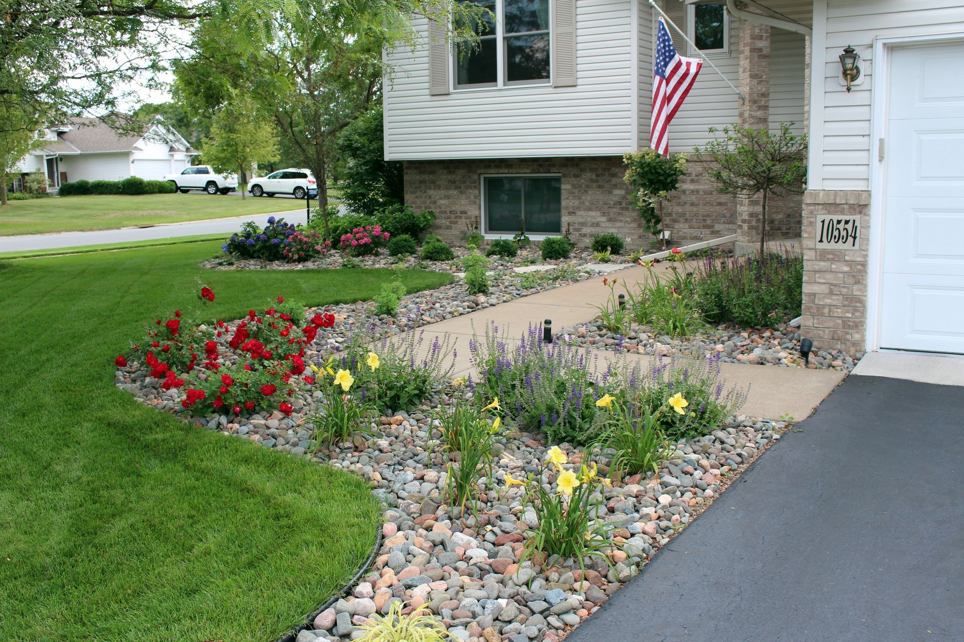 Colorful front yard landscaping beside a front-facing garage in Blaine MN with roses, daylilies, and catmint