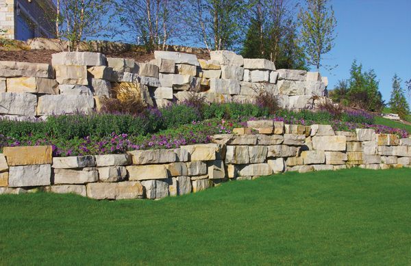 A large stone wall surrounds a lush green field.