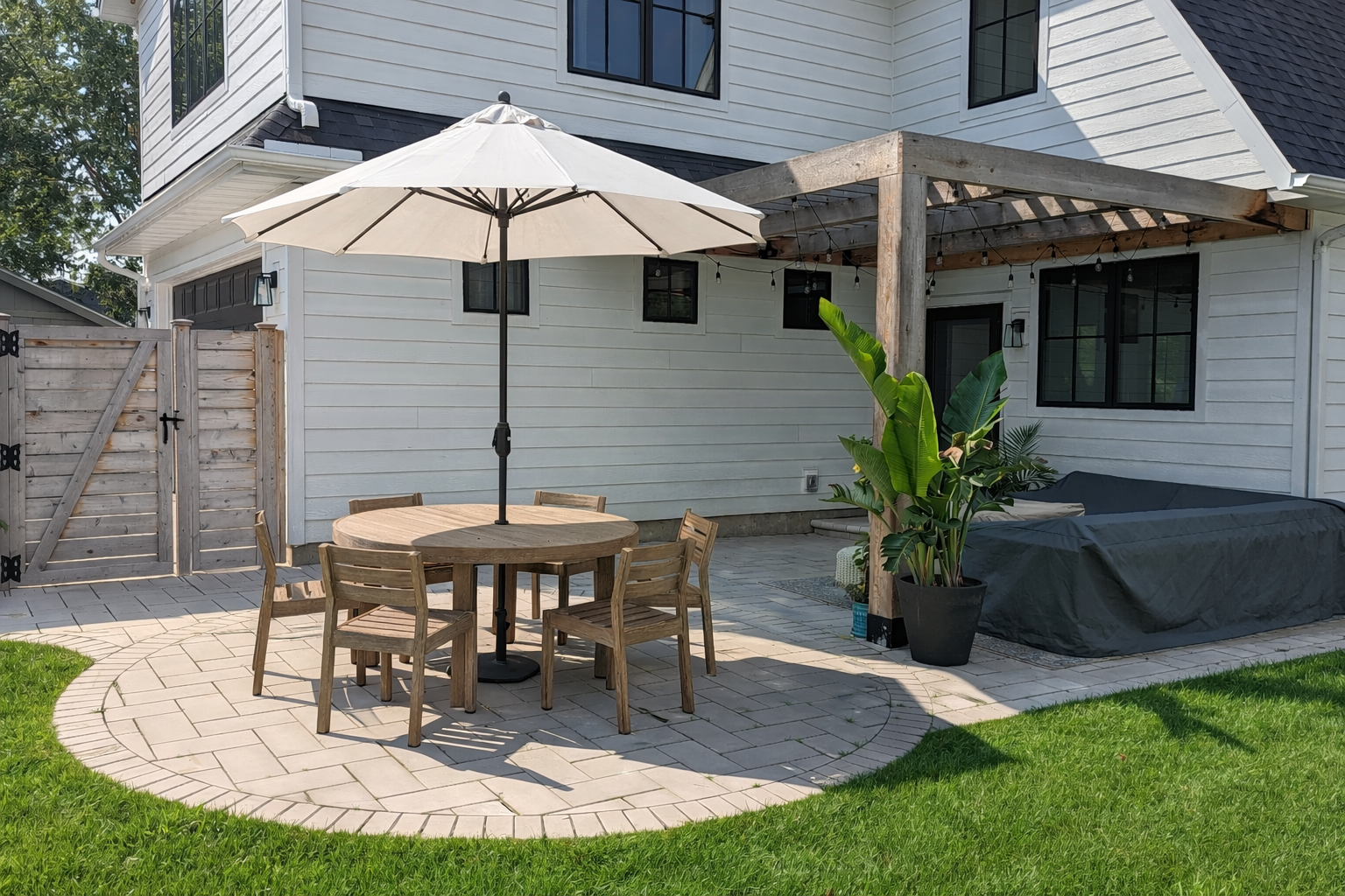 Modern paver patio with light wood pergola in Edina, MN in the spring.