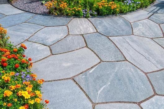 A stone walkway with flowers in the background.
