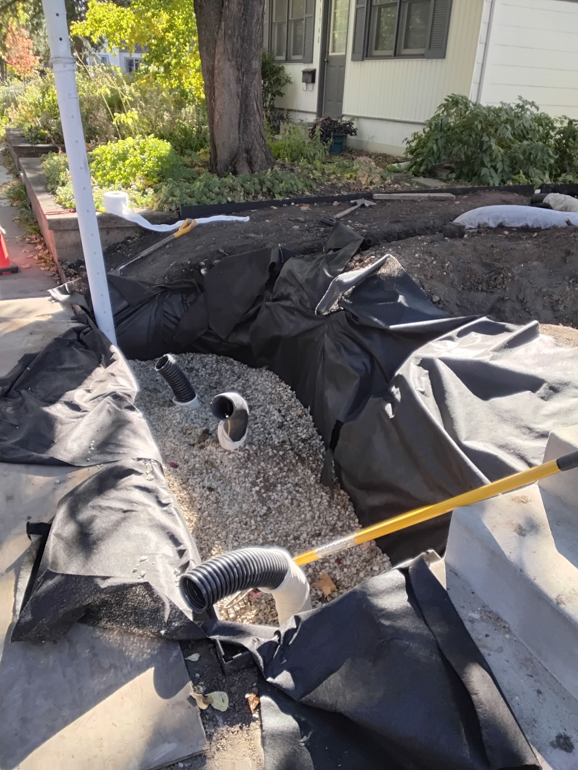 Dry well being installed in a Minneapolis Yard with river rock backfill and drain pipe