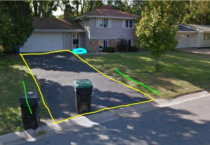 An aerial view of a house with a driveway and trash cans