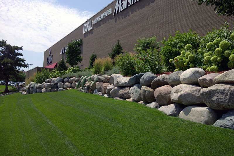 Boulder wall and nice green lawn with good looking plants and shrubs in North Oaks MN