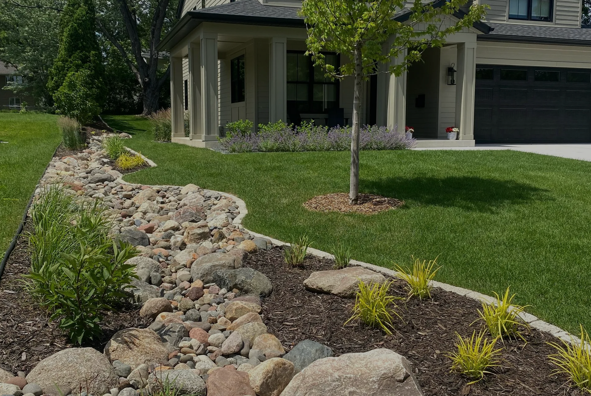 Landscaped front yard with a dry creek bed and a house.