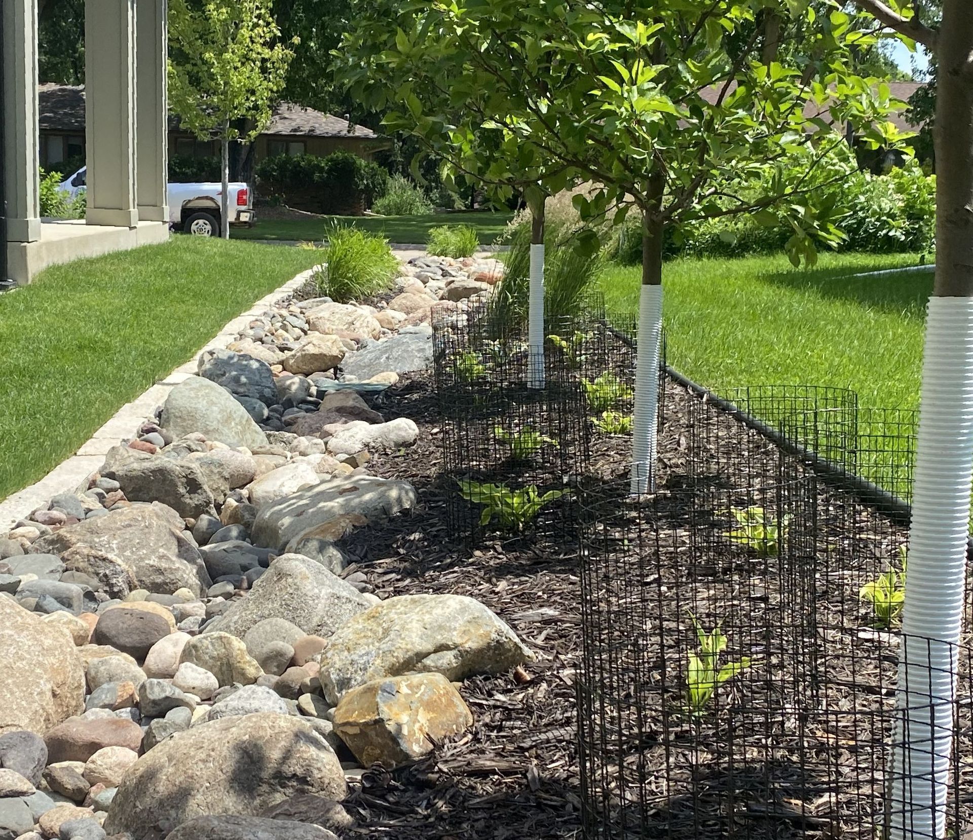 dry creek bed with MN river rock and boulder with nice looking plantings in side yard 