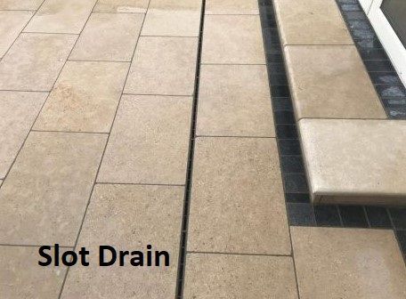 A picture of a slot drain on a tiled floor.