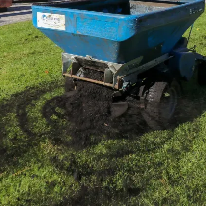 topdressing machine spreading rich compost in lawn