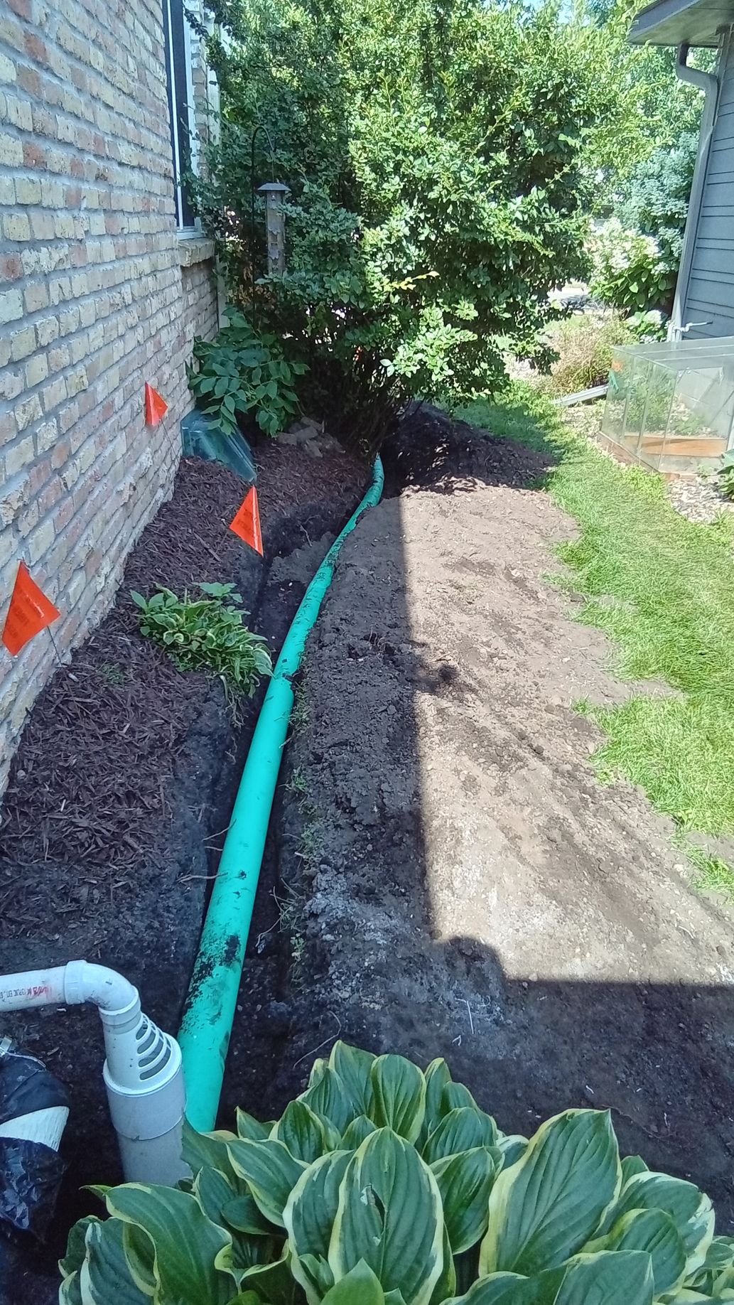 Underground 4 inch non perforated PVC sump pump discharge drain pipe in trench running toward a dry well