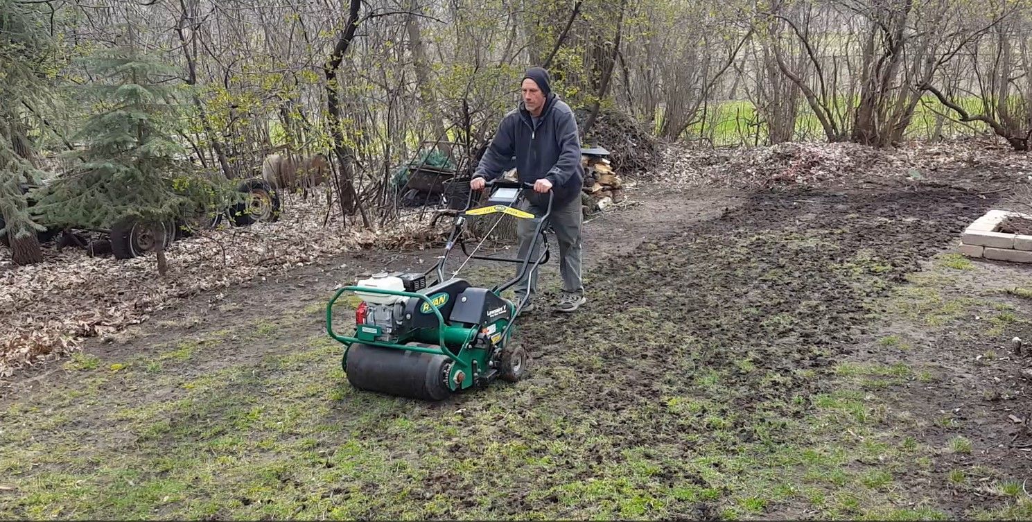 A man is using a lawn mower to mow a lush green lawn.