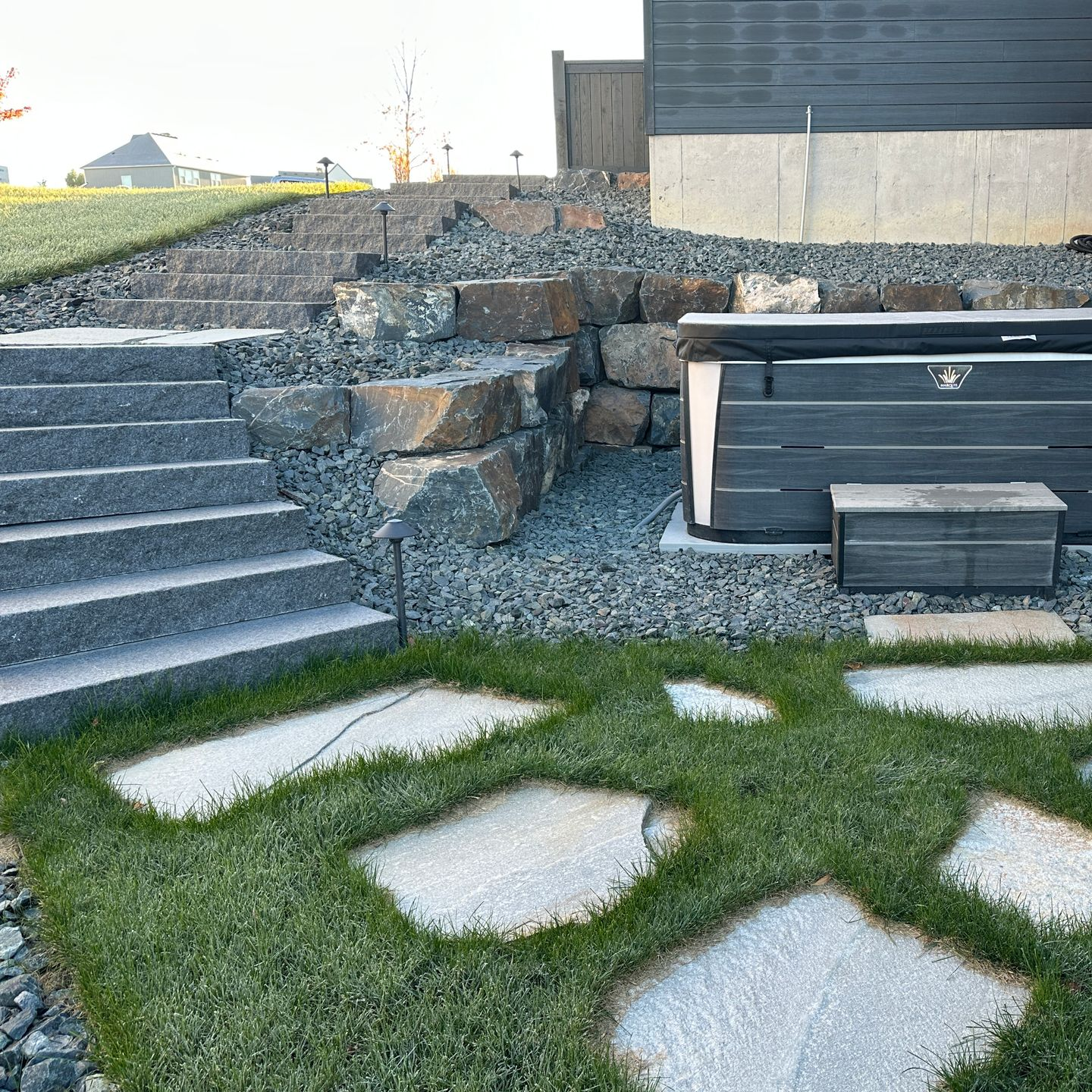 Side yard stone steps and large flagstone pathway with a hot tub built into a hill set in the lawn project by KG Landscape