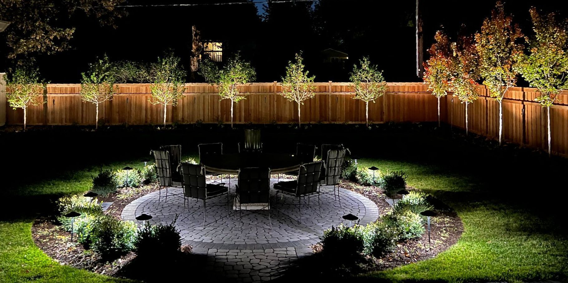 A stone walkway leading to a house with lights on the steps.