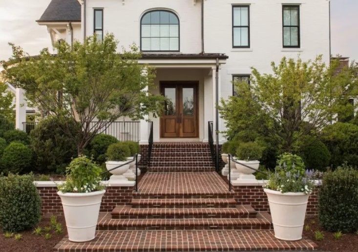 A white house with brick steps leading up to the front door.