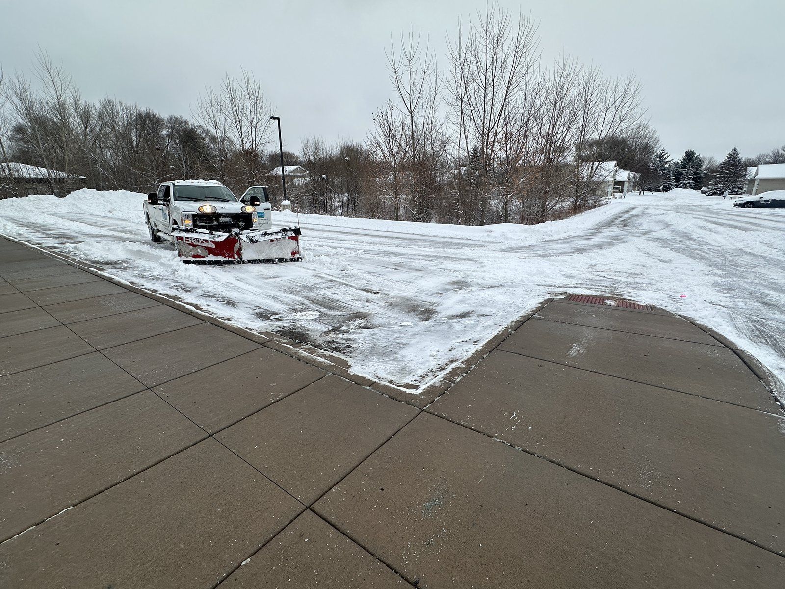 KG Landscape plow truck clearing a parking lot next to a freshly cleared sidewalk