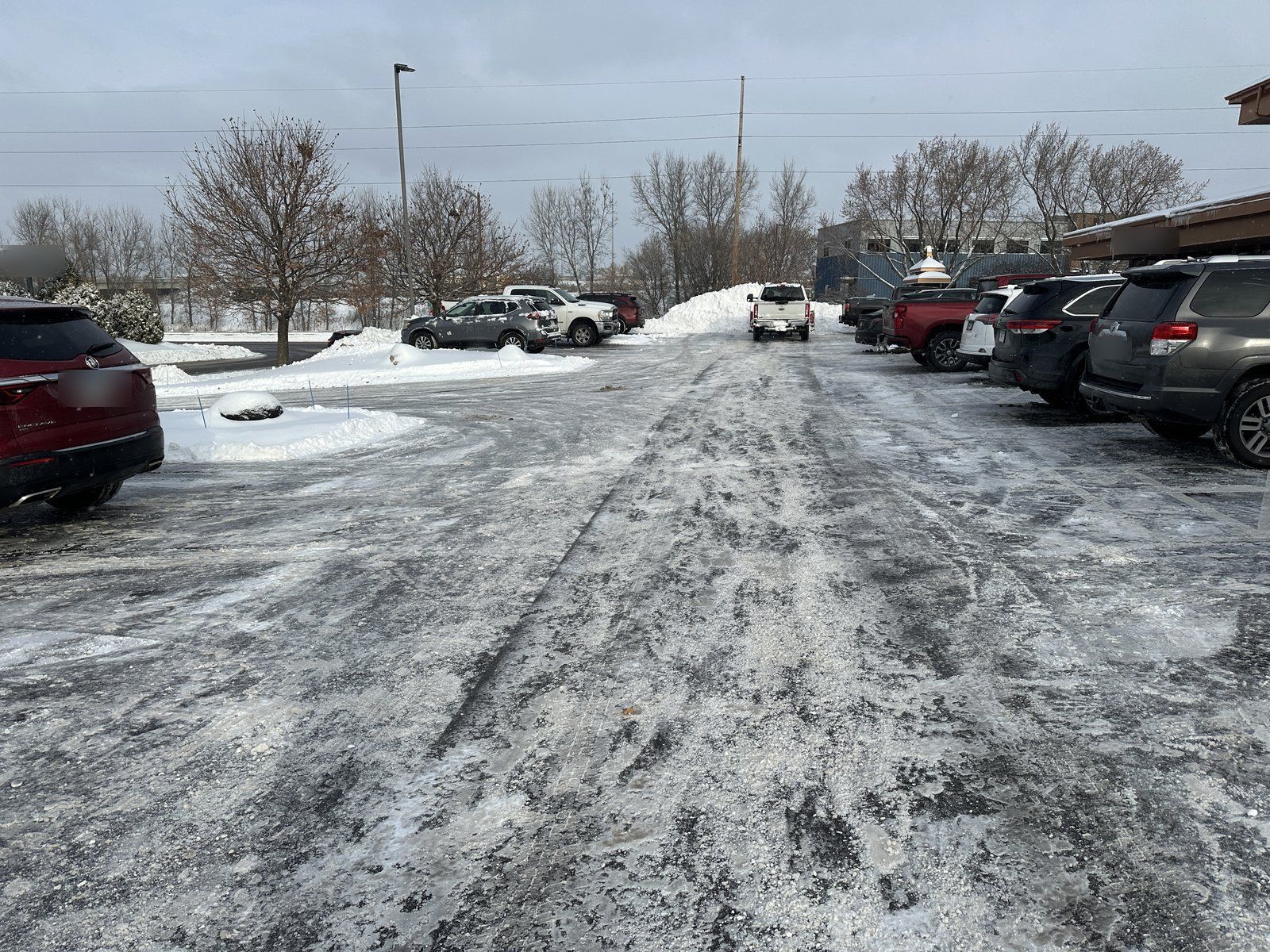 Commercial parking lot treated with salt after plowing, with bare pavement showing