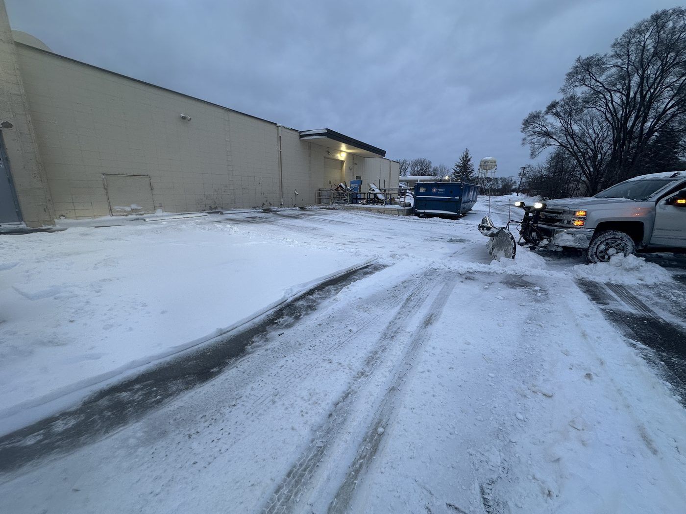 Plow truck opening a drive lane behind a small warehouse