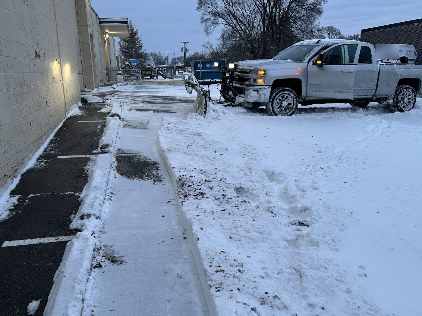 Plow truck beside a warehouse wall with the walk along the building cleared