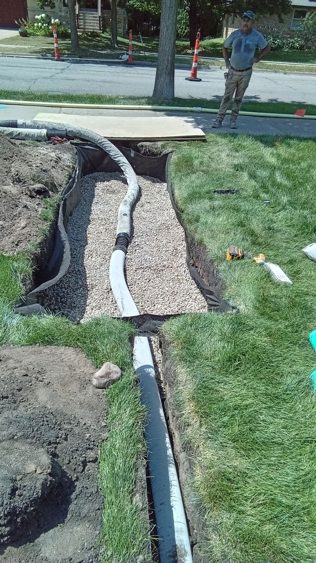 During: shows crew nearing the completing of dry well with rock fill up to drain pipe entry elevation