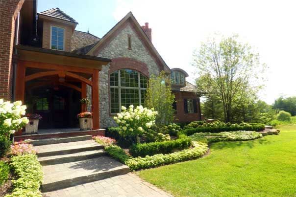 Clean-cut front yard landscaping with flowers, boxwoods, and curved garden beds in Edina MN