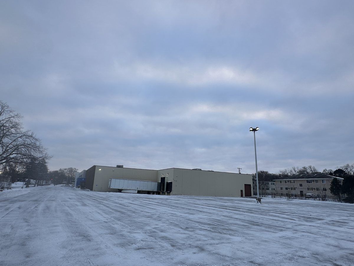 Plowed lot with a warehouse and trailers in the distance
