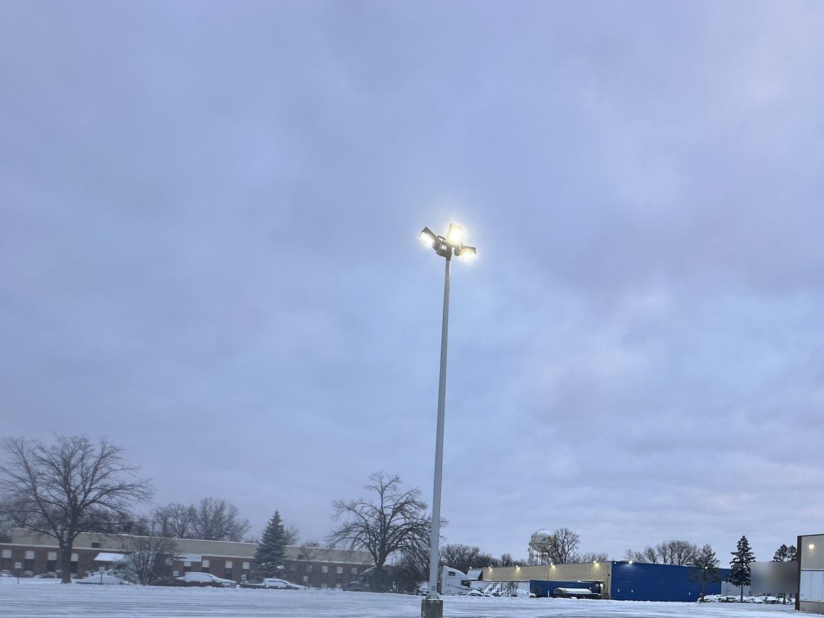 Open plowed lot under a light pole, warehouses in the distance