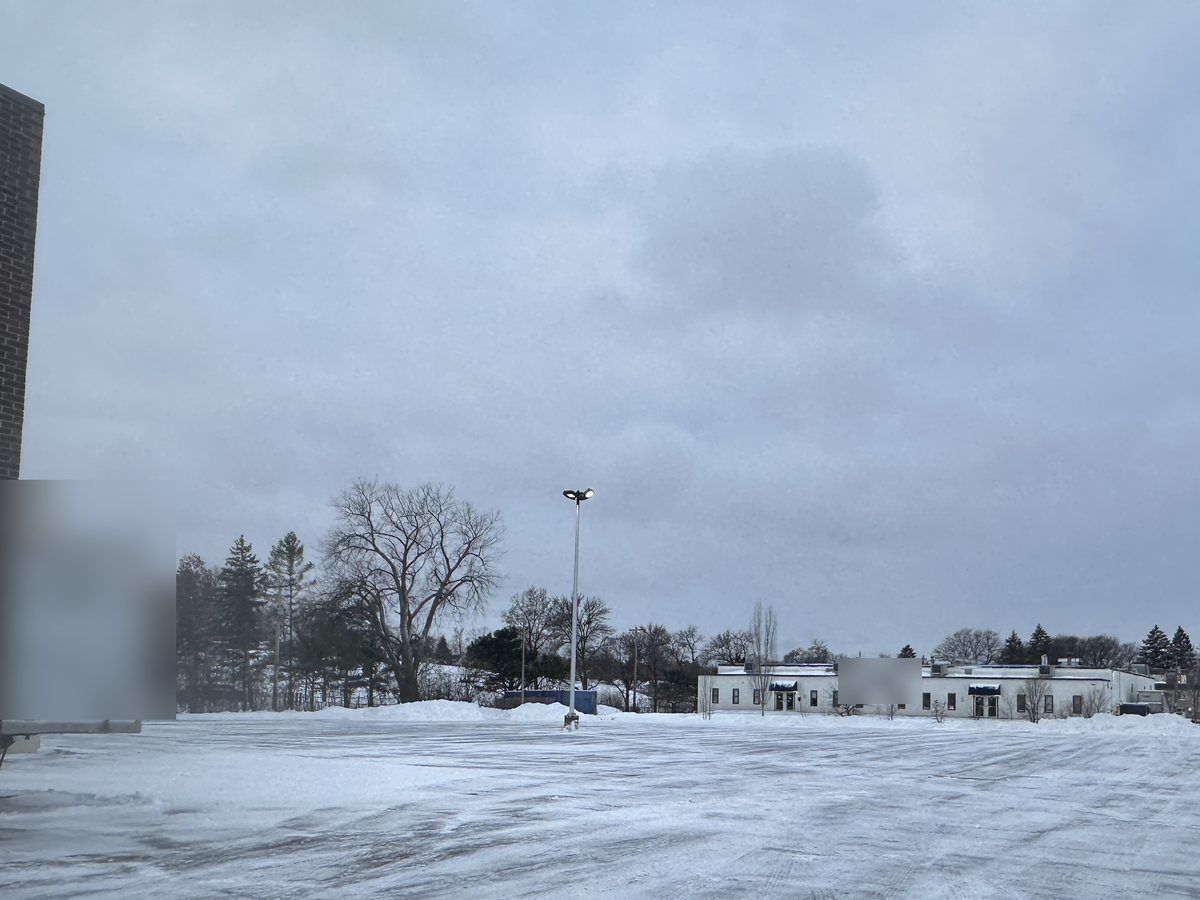 Wide plowed lot with low buildings in the distance