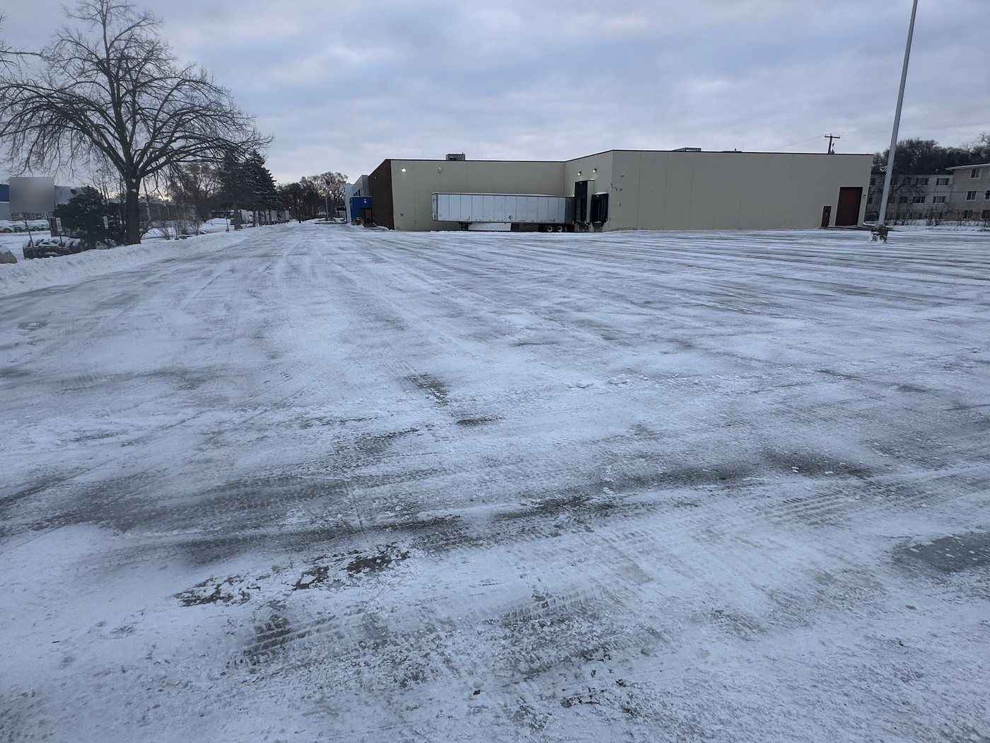 Plowed industrial yard with low warehouse buildings in the distance