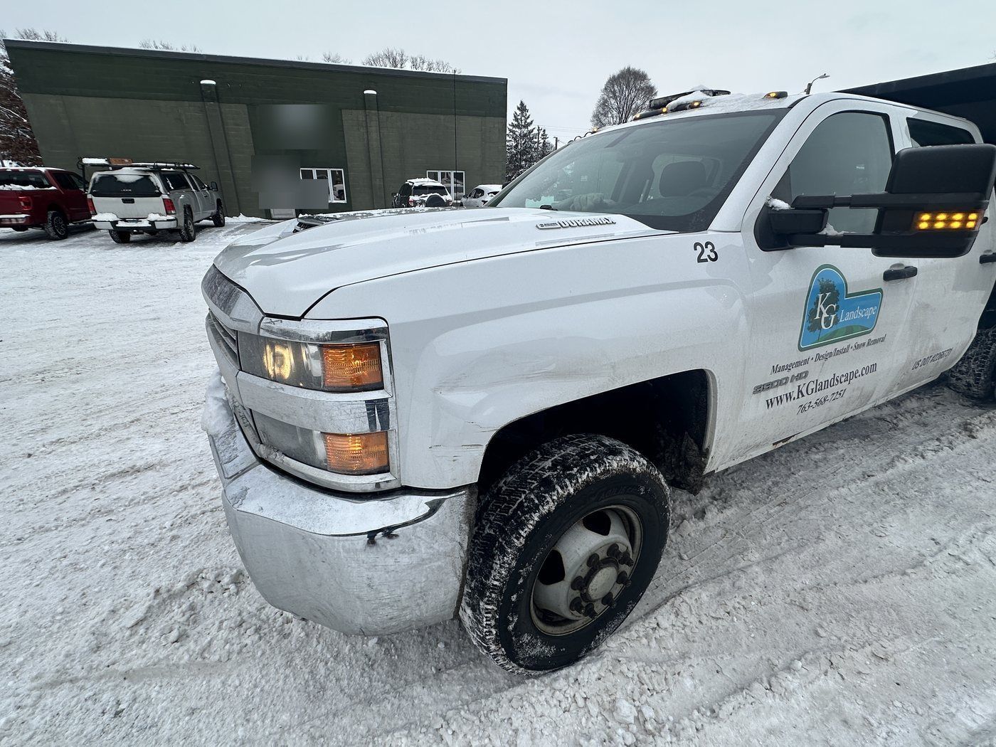 KG Landscape truck parked at an industrial building lot after snow