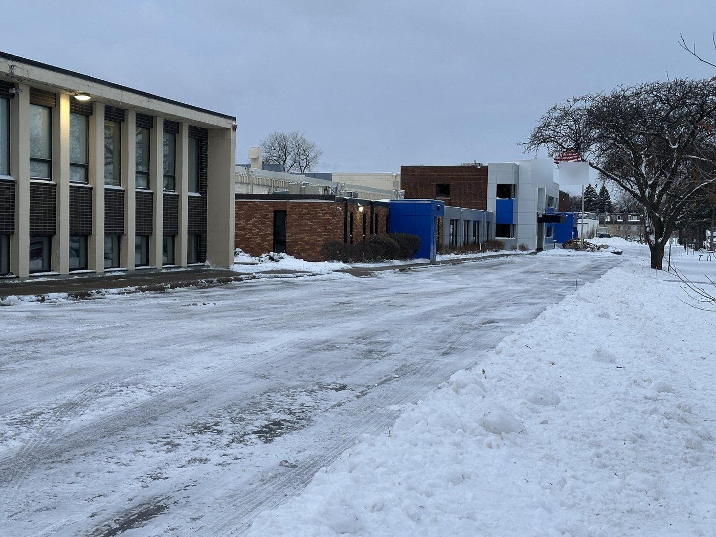 Cleared drive beside an industrial building, plowed snow banked on site