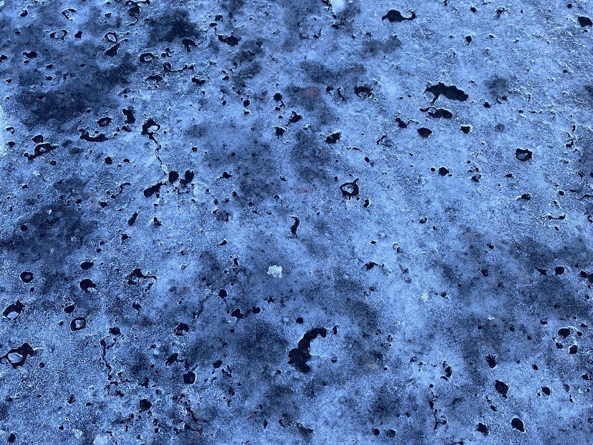 Close view of salt crystals melting through a glaze of ice