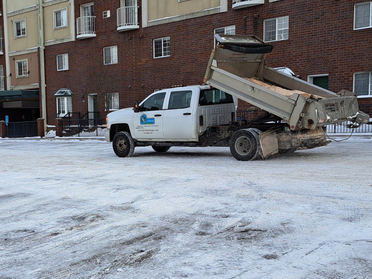 KG Landscape dump truck in a plowed lot in front of an apartment building