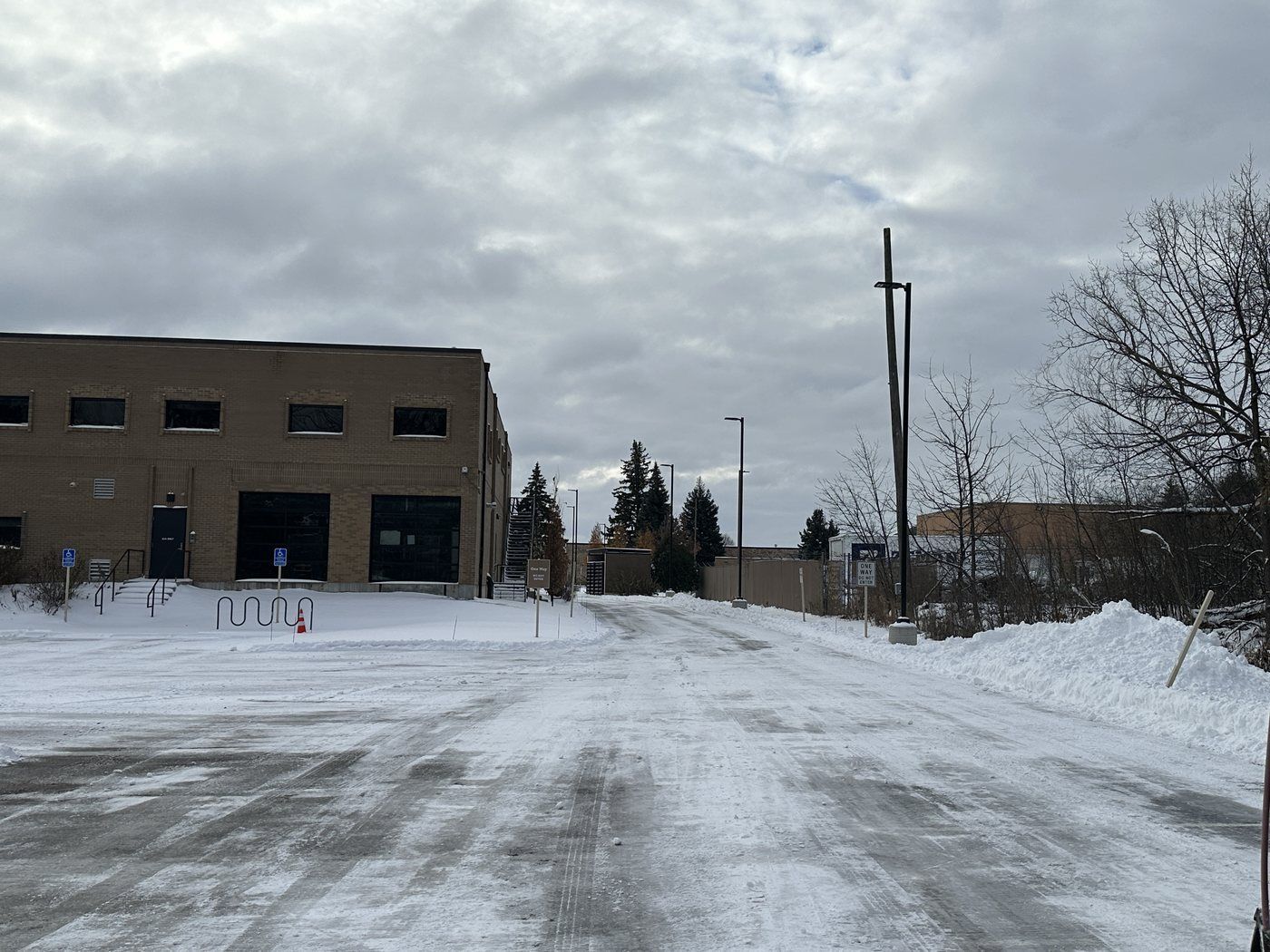 Plowed drive beside a tan brick building, snow banked at its edge