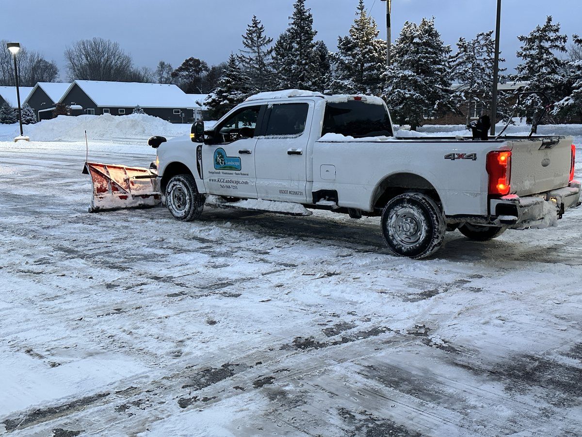KG Landscape pickup with an orange plow at dusk in a cleared lot
