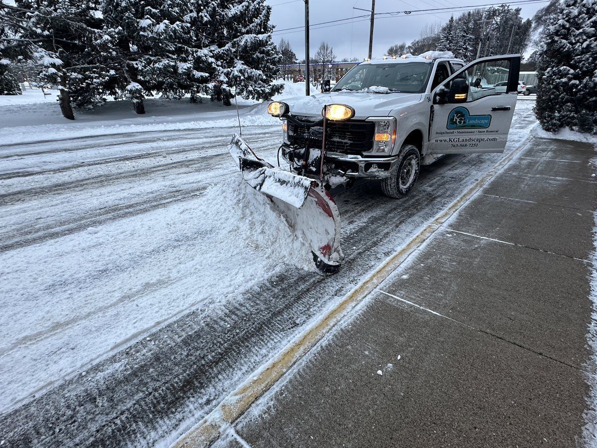 KG Landscape pickup pushing snow beside a cleared walk