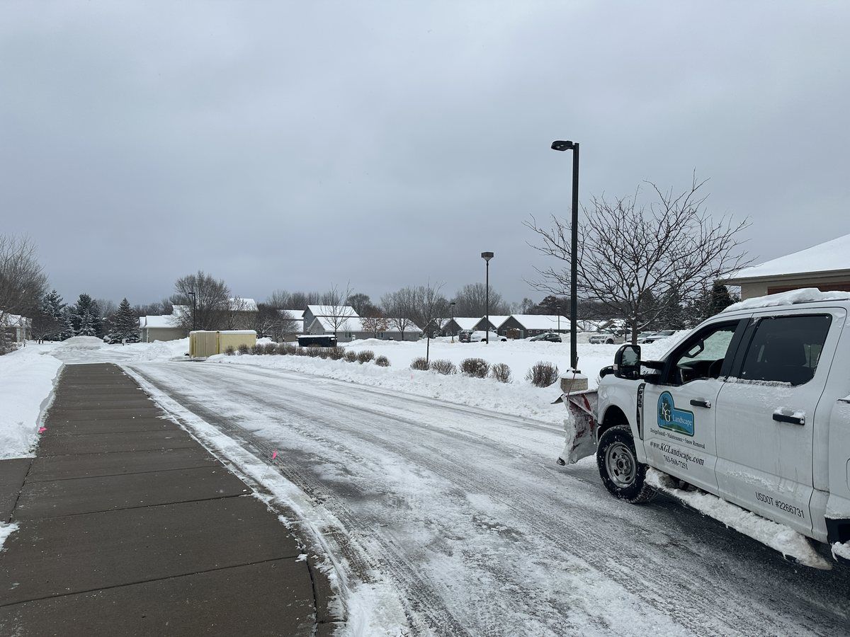 KG Landscape pickup plowing a drive beside a cleared walk