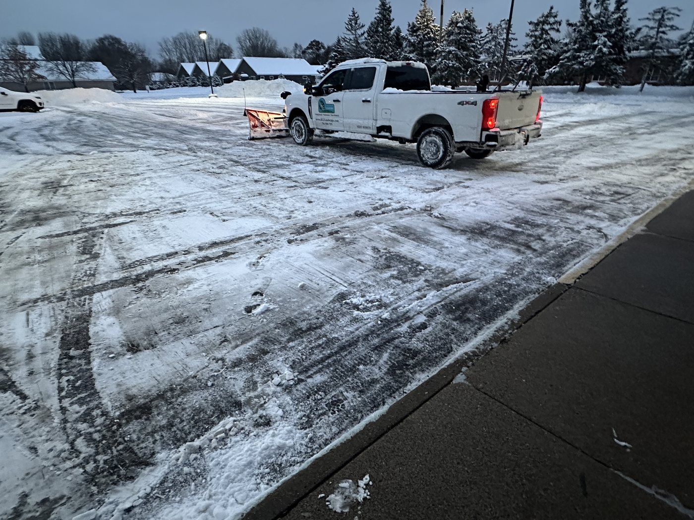 KG Landscape pickup with a plow parked in a plowed parking lot