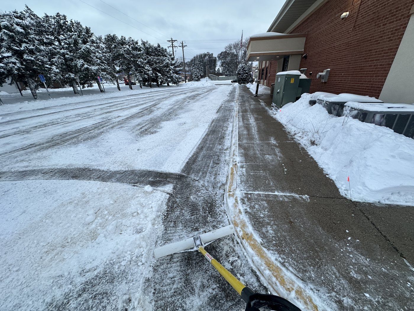 Concrete walk along the side of a brick building scraped clear of snow